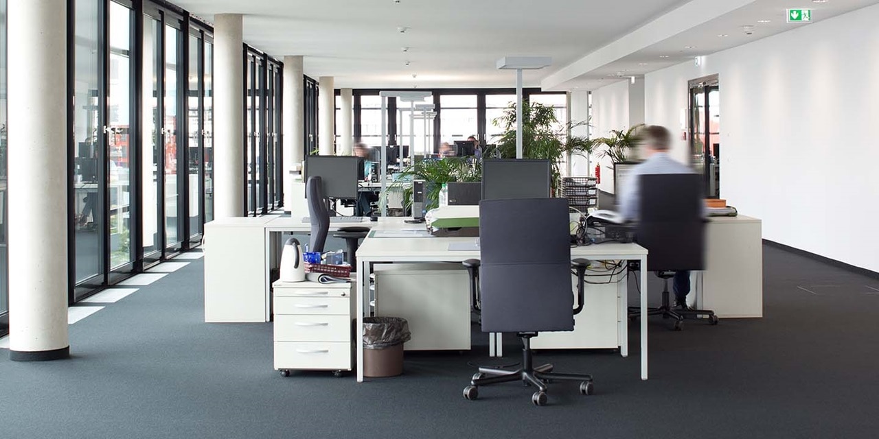 Moderne Büroumgebung mit Schreibtischen, Stühlen und Computern mit einer Person in Bewegungsunschärfe