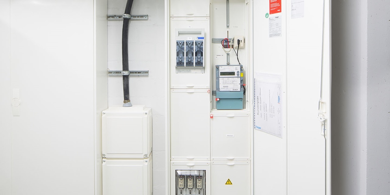 Industrielle elektrische Schaltanlagen und Messgeräte in einem weißen Technikraum installiert