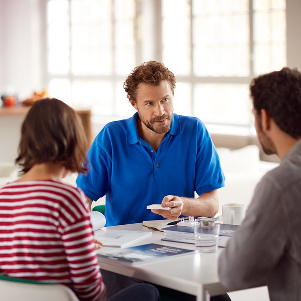 Teambesprechung mit drei Fachleuten, die in einem hellen Büro über Dokumente diskutieren