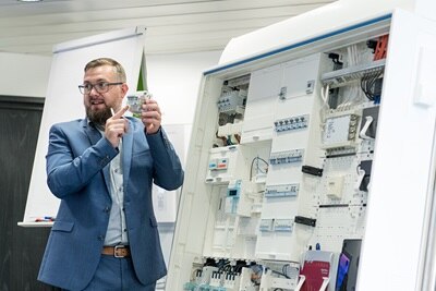 Symbolbild für praxisnahes Präsenzseminar: Hager Referent erklärt unsere Schutzgeräte sowie den Zählerschrank und die dazugehörigen Normen