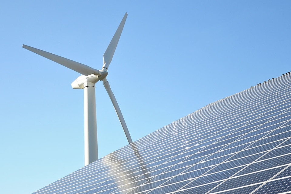 Solarmodule mit einer Windturbine vor klarem blauem Himmel, Darstellung von erneuerbaren Energiequellen