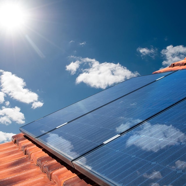 Auf einem Dach unter der Sonne installierte Solarmodule mit einem klaren blauen Himmel