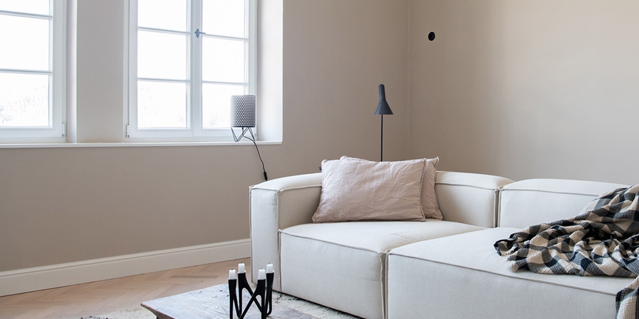 Minimalistisches modernes Wohnzimmer mit weißem Sofa, Stehlampe und karierte Wolldecke