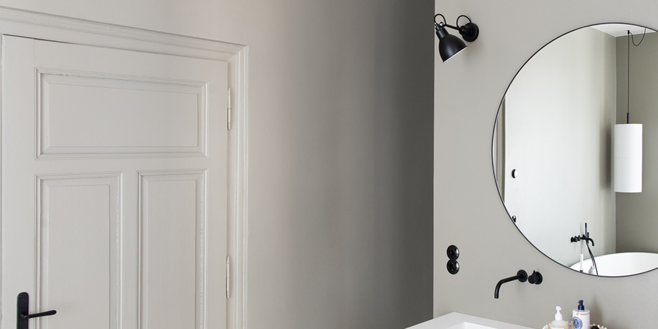 Elegantes Badezimmerinterieur mit rundem Spiegel und modernen Wandleuchten