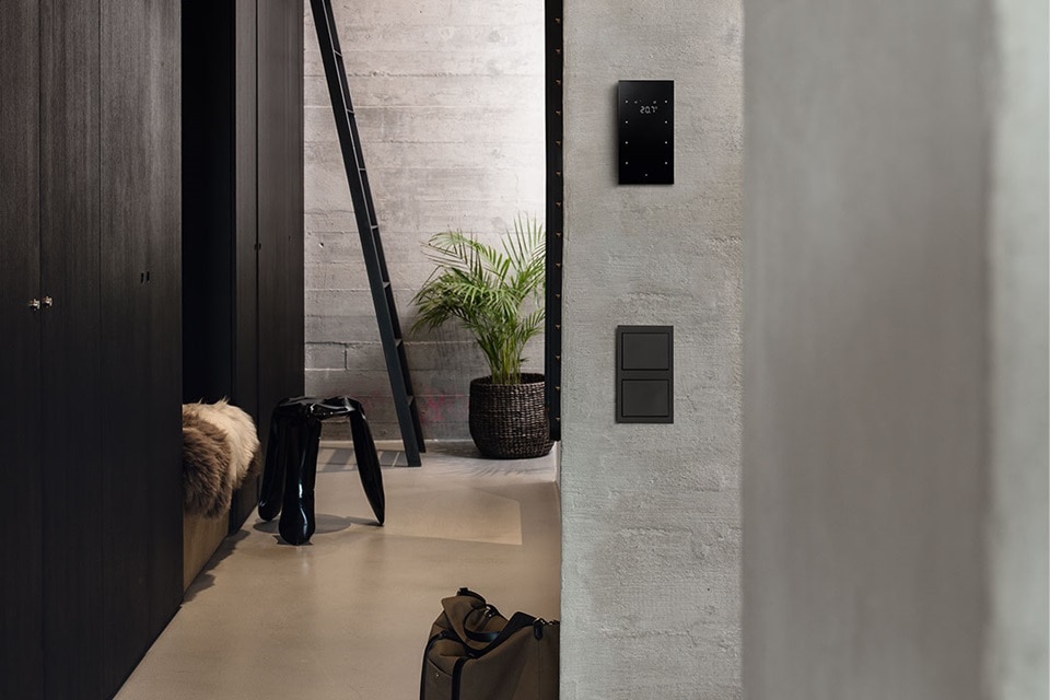 Modernes Interieur mit Smart-Home-Touchscreen-Panel und Lichtschalter an Betonwand