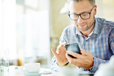 Ein Mann, der mit dem Handy seine Energiedaten über das Energiemanagementsystem flow abruft.