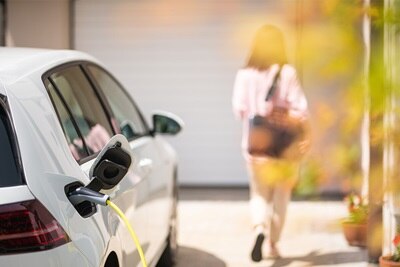 Ein Elektroauto hängt an einem Ladegerät, während es in einer Hauseinfahrt parkt