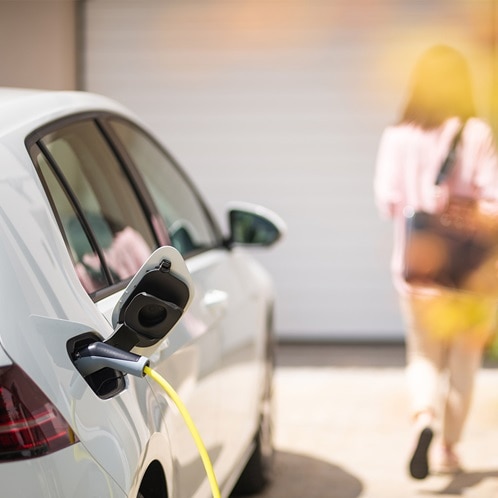 Ein Elektroauto hängt an einem Ladegerät, während es in einer Hauseinfahrt parkt