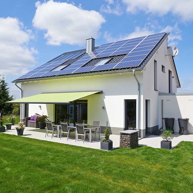 Modernes Haus mit Solarmodulen auf dem Dach und einem gepflegten Garten