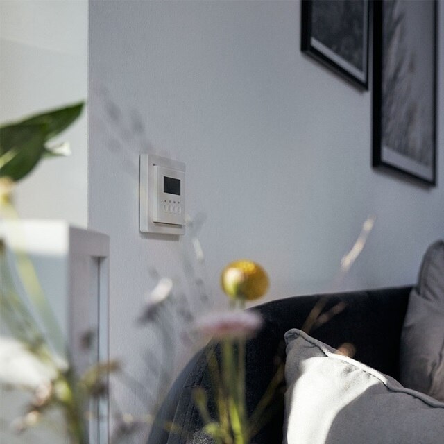 Thermostat an einer Wohnzimmerwand mit moderner Einrichtung und Möbeln
