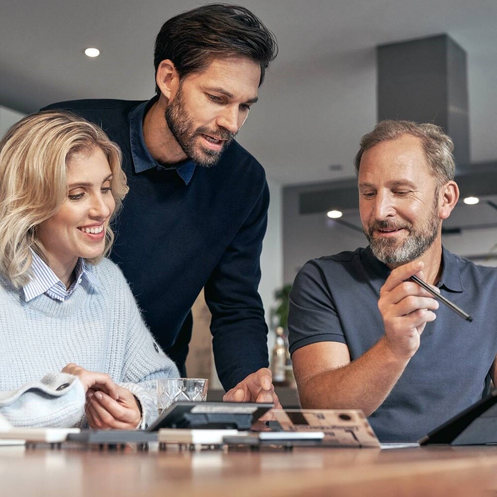 Drei Fachleute diskutieren über elektrische Bauteile und Automatisierungswerkzeuge im Büro