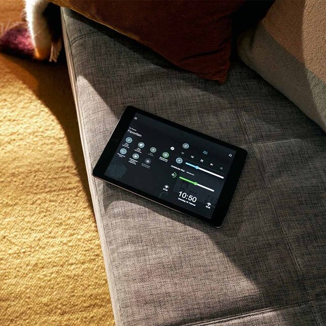 Tablet zur Steuerung des Smart Homes auf einer Couch in einem Wohnzimmer