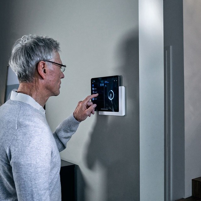 Person stellt Einstellungen an einem an der Wand montierten Touchscreen-Bedienfeld für Hausautomation vor