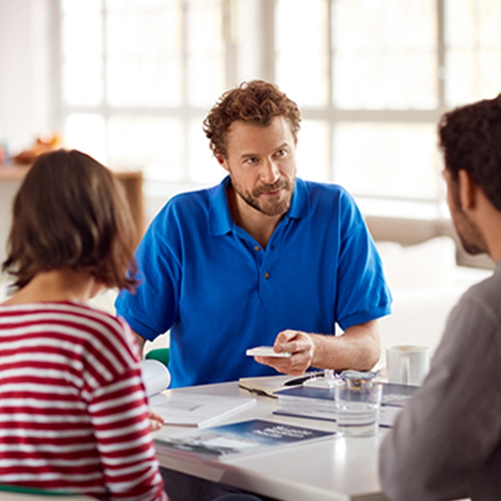 Besprechung im Büro mit drei Mitarbeitern, die über Dokumente diskutieren