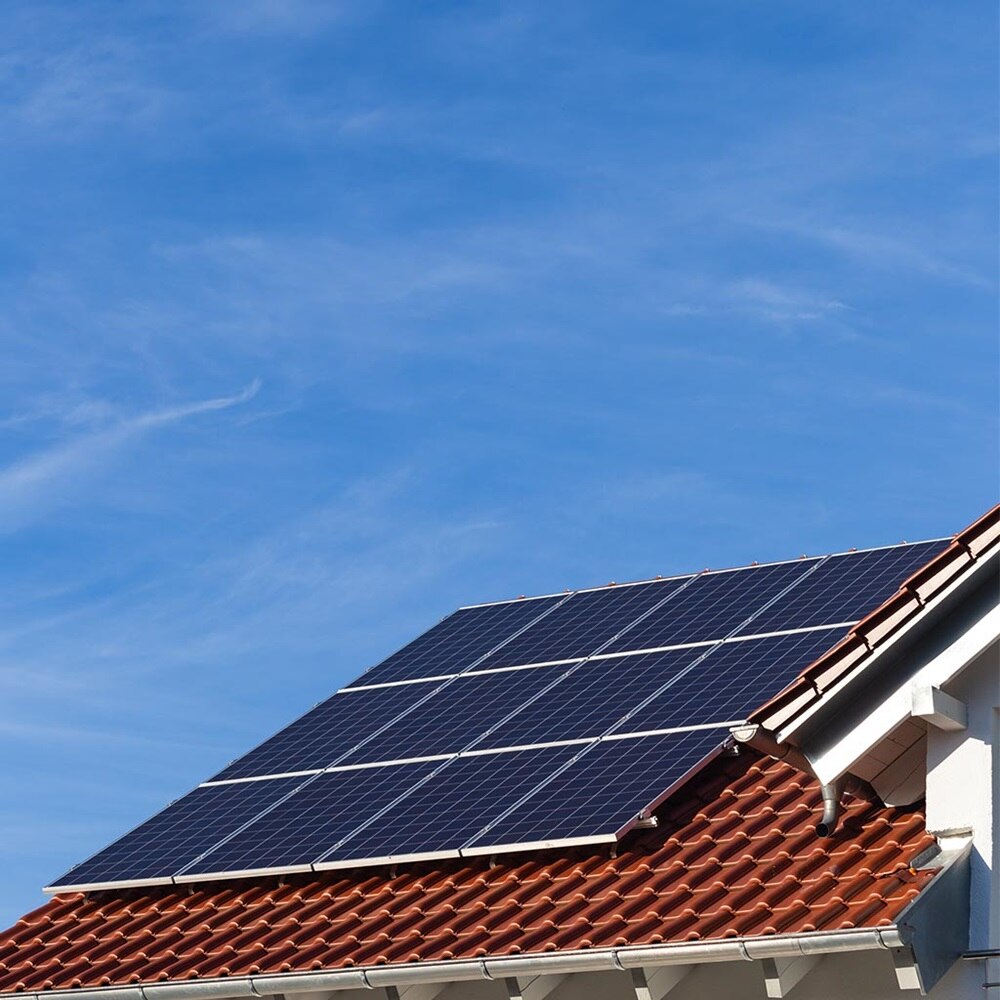 Solarpaneele auf einem Wohnhausdach gegen einen klaren blauen Himmel