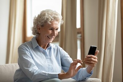 Eine Frau sitzt mit ihrem Handy auf der Couch