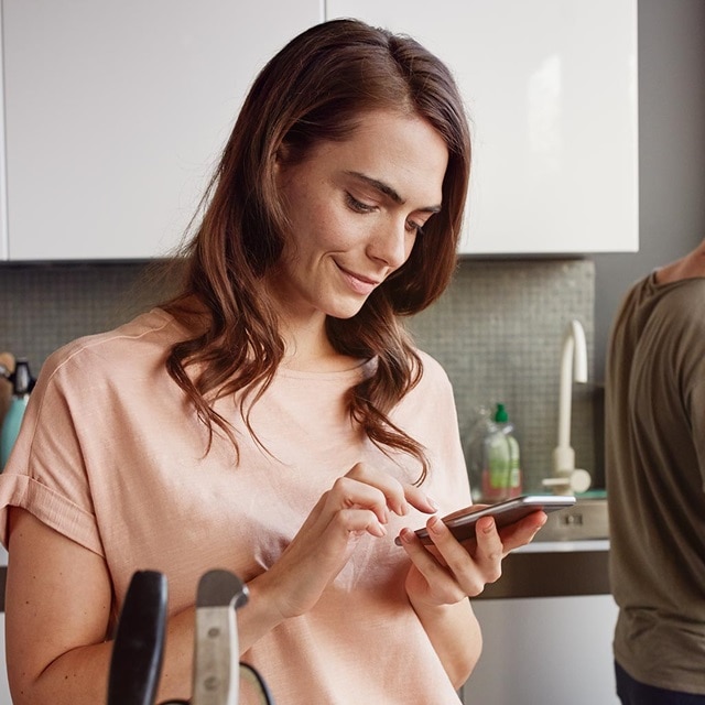 Person benutzt ein Smartphone in einer Küche, möglicherweise zur Steuerung eines Hausautomationssystems