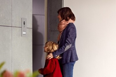 Eine Mutter mit Kind stehen vor einer Haustür.