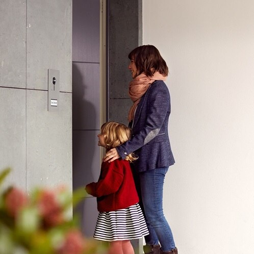 Eine Mutter mit Kind stehen vor einer Haustür.