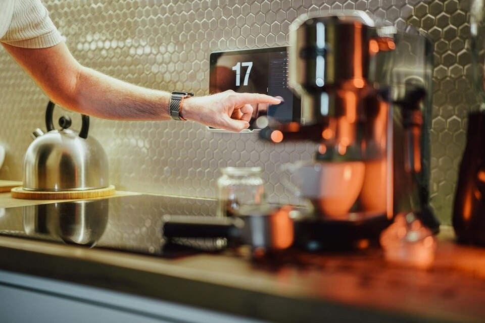 Eine Person bedient ein digitales Kaffeemaschinen-Display in einer modernen Küche
