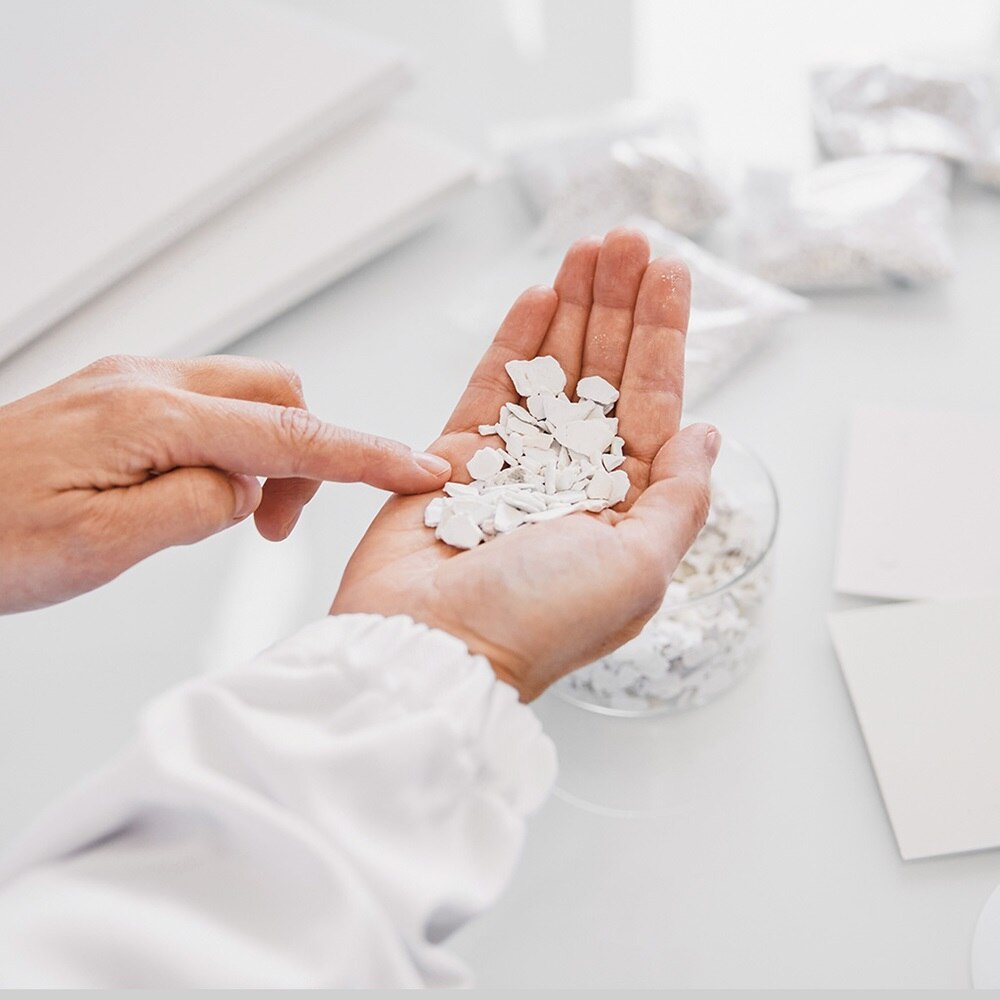 Hager Group Hand mit weißen Plastikstücken, das für neue Produkte recycelt wird