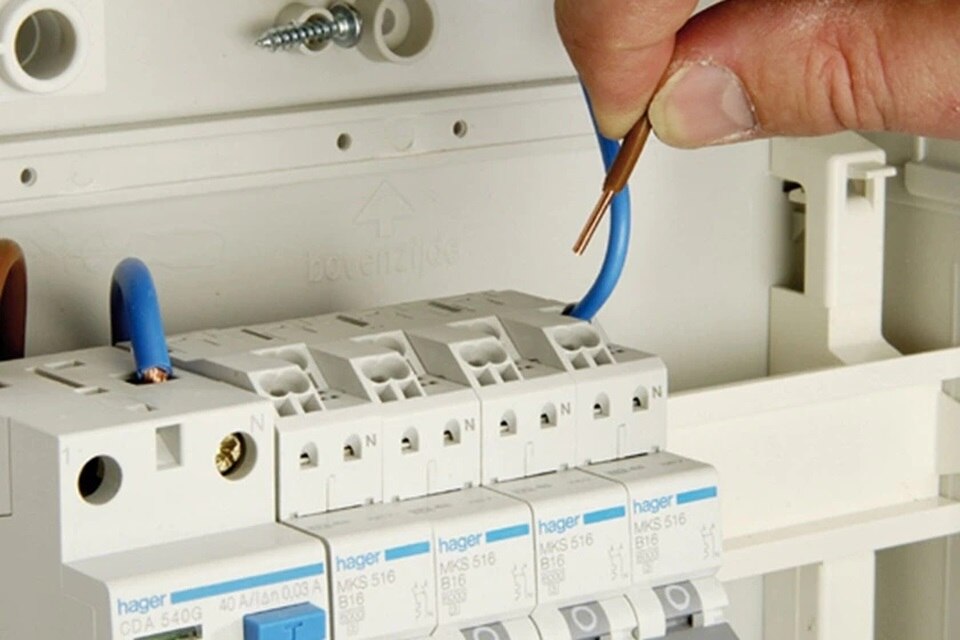 Electrician connecting wires to a Hager circuit breaker in an electrical enclosure