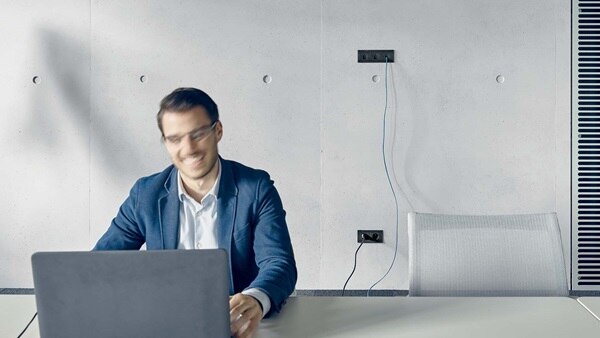 Person working on laptop in a modern office with electrical outlets on the wall