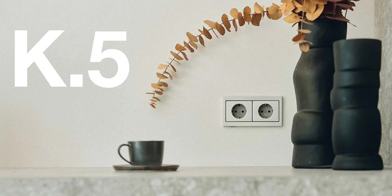 Modern interior with double electrical socket, decorative vase, and cup on counter