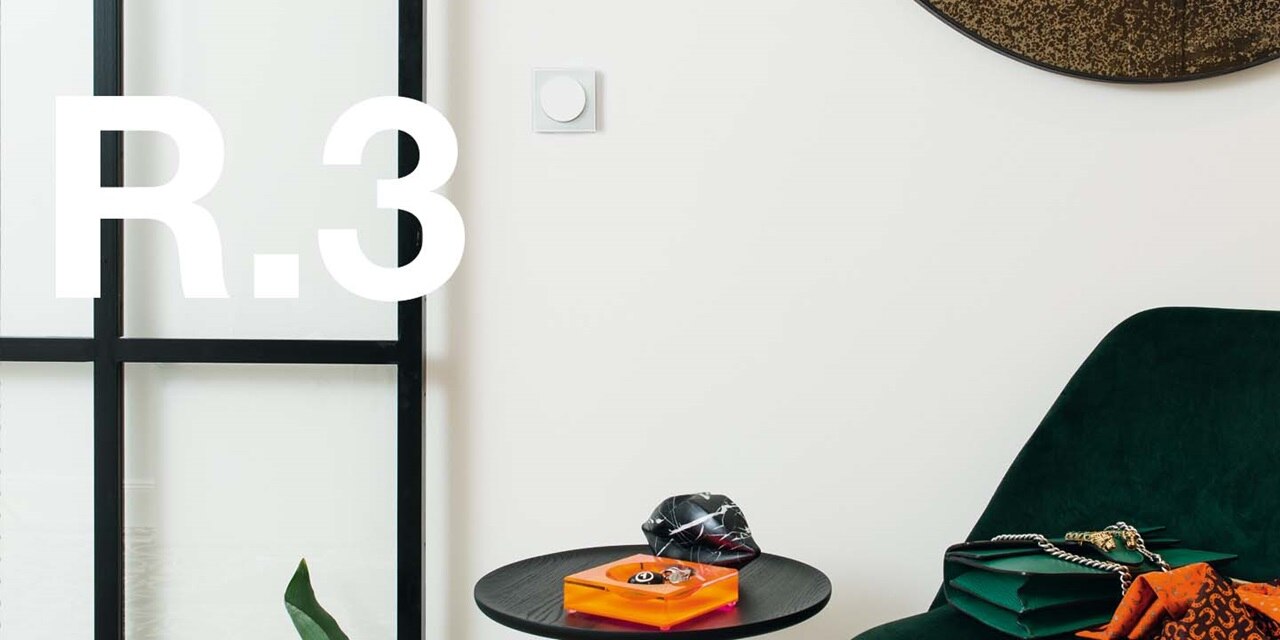 Modern interior with a light switch on the wall, emerald green armchair, and decorative items on a coffee table