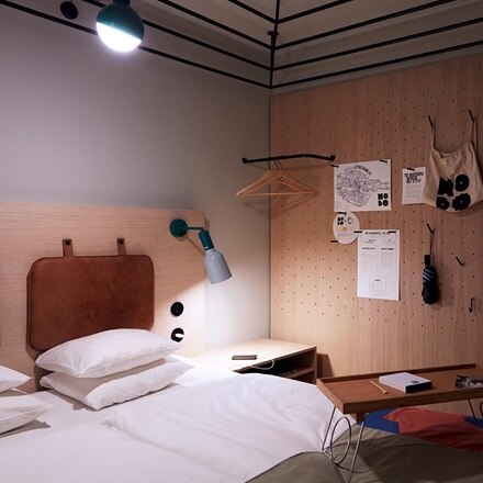 Modern bedroom interior with wall-mounted bedside lamps and pegboard wall organizer