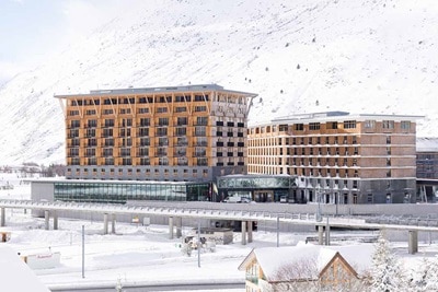 Modern buildings with wooden facades in a snowy landscape with mountains in the background