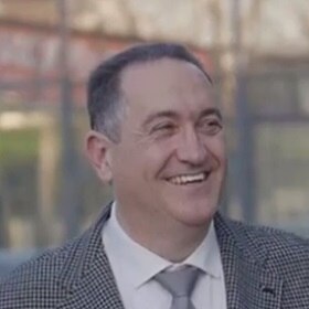 Smiling individual wearing a checked blazer outdoors