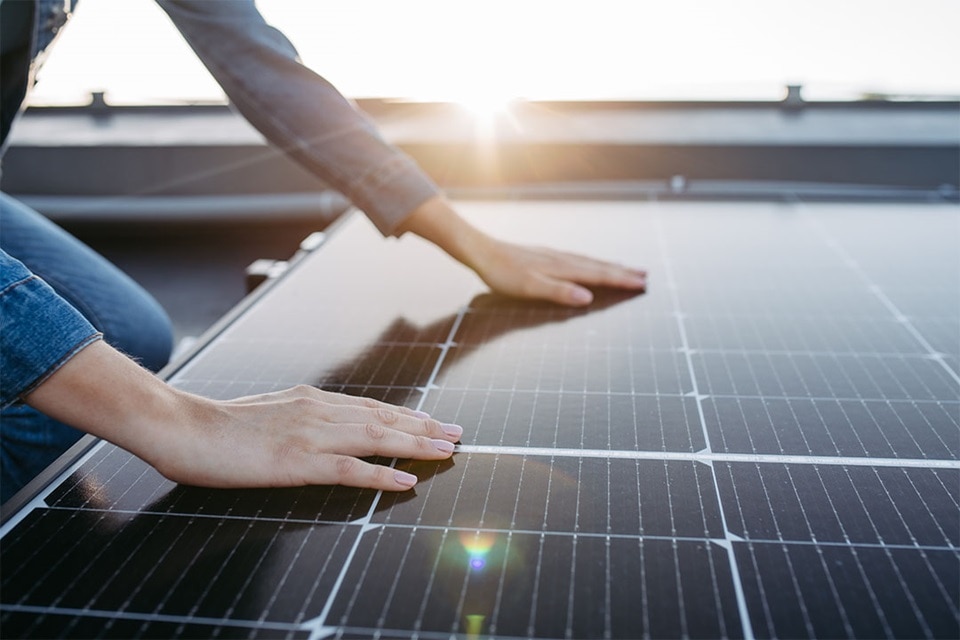 Hager Group person touchs Solar panel on a roof