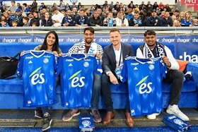 Hager Group 4 people sitting in front of an audience and hold football jerseys in hand