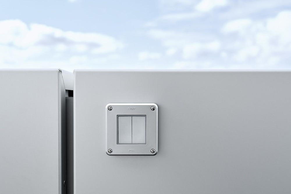 Hager Group light switches of the kallysto and robusto range on a glass wall and blue sky in the background