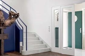 hager group white stone staircase with blue banister and green door in the background