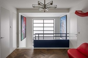 hager group Gallery in the staircase with red design couch on wooden floor