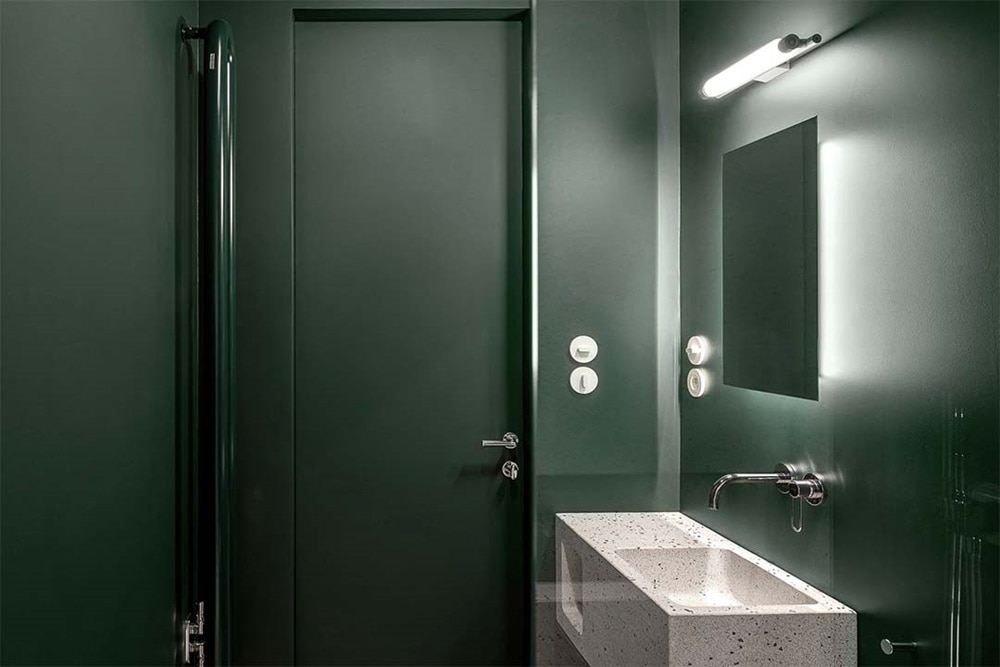hager group design bathroom with dark green walls and white porcelain washbasin