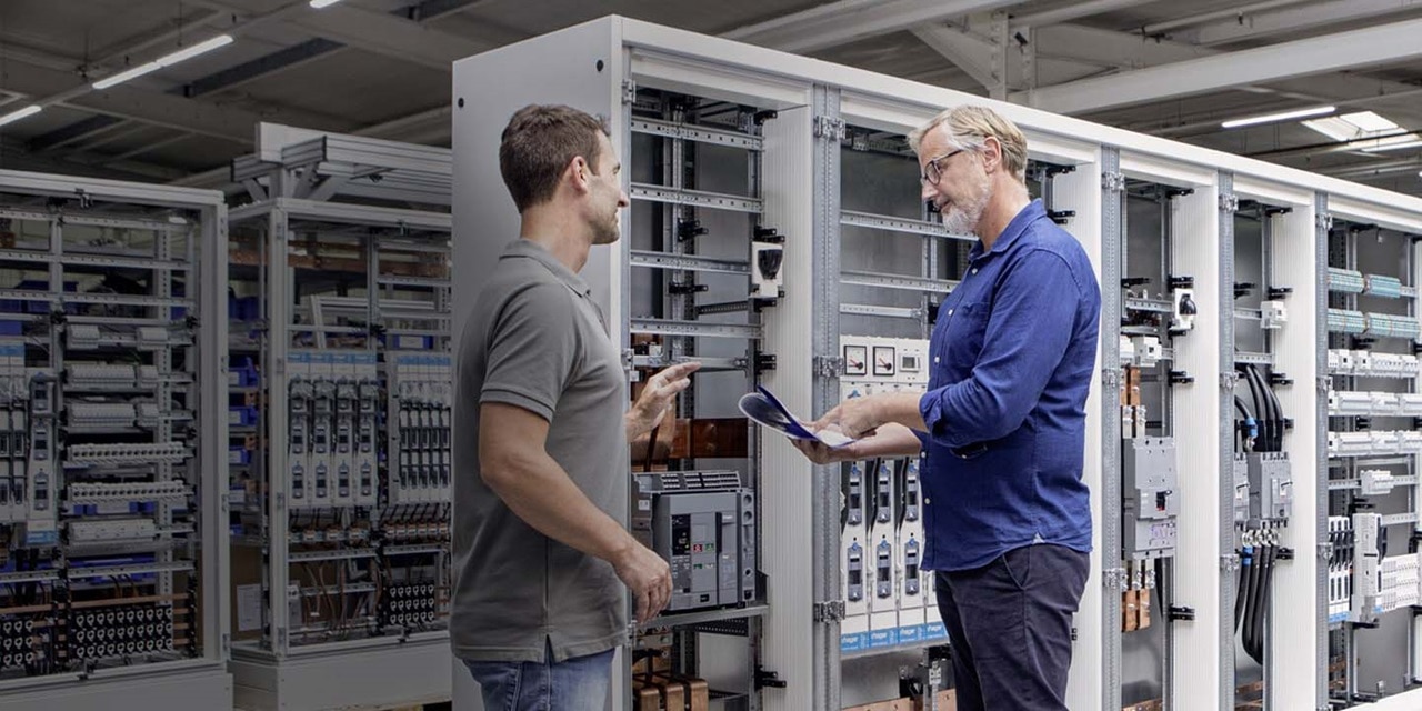 hager employees standing infront of a hager switchboard