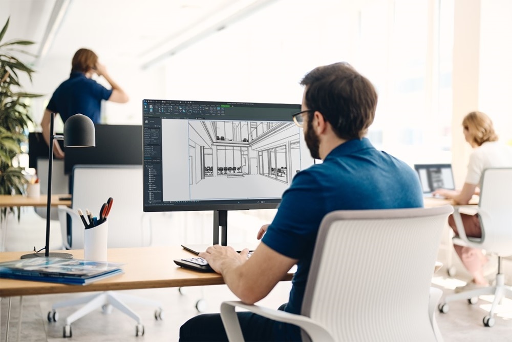 Professional working on a CAD design of a building interior on a computer monitor in an office environment