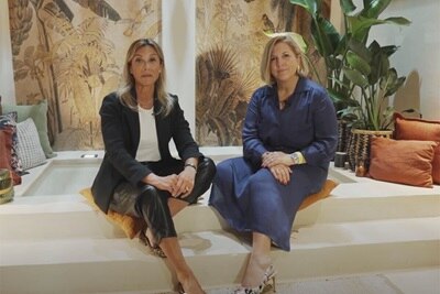 Dos personas sentadas en un interior moderno con papel tapiz tropical y plantas