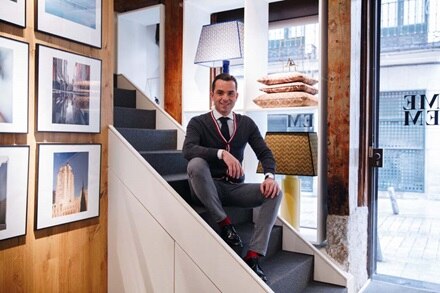 Persona sentada en escaleras en un entorno de oficina moderno con cuadros enmarcados y lámparas estilizadas