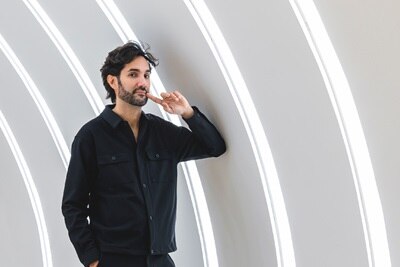 Persona posando frente a paneles de luz LED curvos en un interior moderno