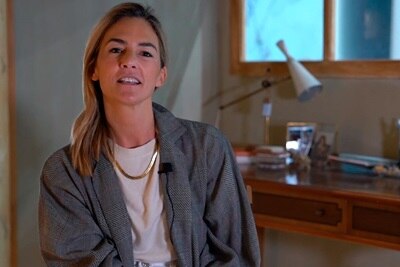 Persona con blazer de cuadros hablando en un ambiente de oficina con una lámpara de escritorio de fondo