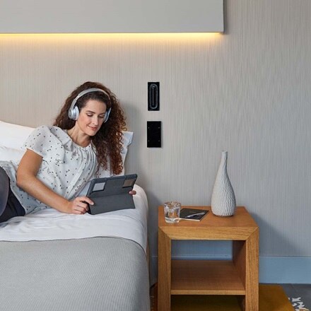 femme assise sur un lit et regardant une tablette dans une chambre d'hôtel à l'Hôtel Sorli Emocions à Barcelone