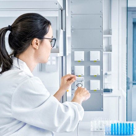 Une femme dans un laboratoire avec six prises électriques contre le mur. Elle branche un appareil sur une prise.