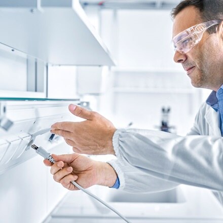 un technicien de laboratoire portant un tablier blanc et des lunettes de sécurité se branche sur la prise