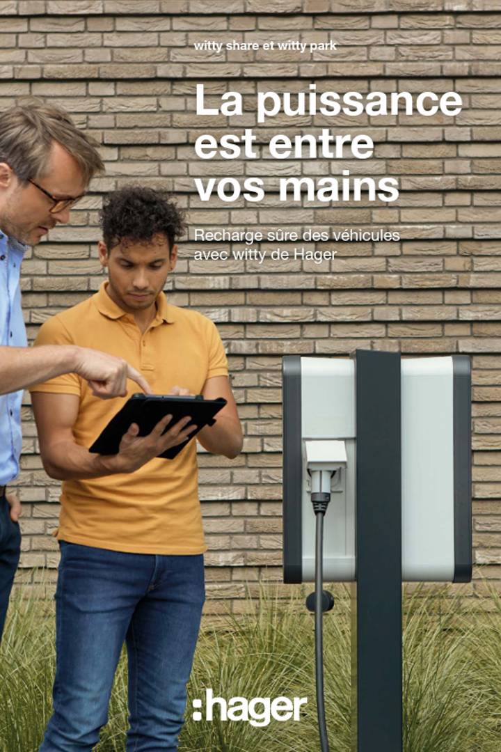 Deux personnes utilisant une tablette à côté d'une borne de recharge de véhicule électrique Hager Witty