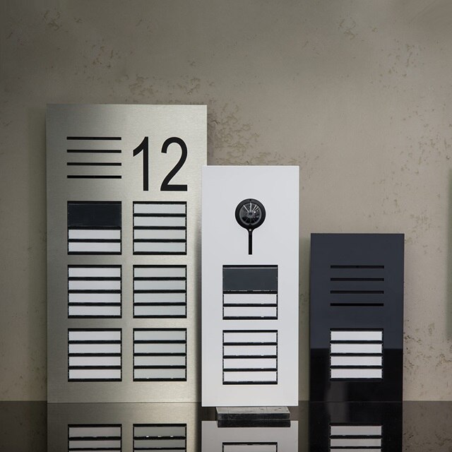 Panneaux de sonnette modernes avec numéros d'appartement et interphone sur un mur en béton
