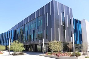 Bâtiment commercial moderne avec façade en verre réfléchissant et panneaux bleus